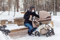 Father with a stroller is resting on a park bench. Winter Russia Royalty Free Stock Photo