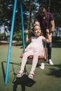 Father swaying his daughter on swing in playground Royalty Free Stock Photo