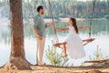 A father swings his daughter on a swing on the shore of a forest lake Royalty Free Stock Photo