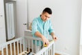Father with tablet pc and ruler measuring baby bed