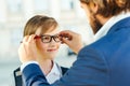 Father takes child to school. Dad puts on his son glasses. Pupil of primary school in eyewear. Back to school