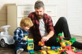 Father takes part in game with son playing on floor holding toy cars. Father and son create toys from bricks. Dad and Royalty Free Stock Photo