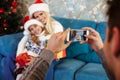 Father taking photo of his cheerful wife and daughter in Santa`s