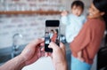 Father taking a picture of mother and baby on a phone in the kitchen of their family house. Love, care and man taking Royalty Free Stock Photo