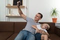 Father taking selfie with his son sitting and making faces. Father and son having fun together Royalty Free Stock Photo