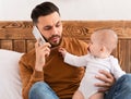 Father Talking On Phone Sitting With Baby Toddler In Bedroom Royalty Free Stock Photo