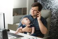 Father talking by phone and taking care of his baby Royalty Free Stock Photo