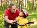 Father talking to his daughter, which teaches to ride a bike Royalty Free Stock Photo