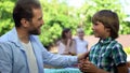 Father talking to son, mom speaking with daughter on background, parenthood