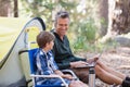 Father talking to son while using laptop in forest Royalty Free Stock Photo