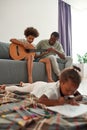 Father teach son play on guitar while girl draw