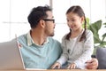Father teaches cute girl daughter to do school homework, using laptop computer for e-learning study at home, happy family dad and Royalty Free Stock Photo