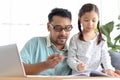 Father teaches cute girl daughter to do school homework, using laptop computer for e-learning study at home, happy family dad and Royalty Free Stock Photo