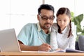 Father teaches cute girl daughter to do school homework, using laptop computer for e-learning study at home, happy family dad and Royalty Free Stock Photo