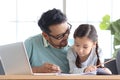 Father teaches cute girl daughter to do school homework, using laptop computer for e-learning study at home, happy family dad and Royalty Free Stock Photo