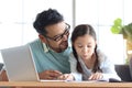 Father teaches cute girl daughter to do school homework, using laptop computer for e-learning study at home, happy family dad and Royalty Free Stock Photo