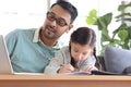 Father teaches cute girl daughter to do school homework, using laptop computer for e-learning study at home, happy family dad and Royalty Free Stock Photo