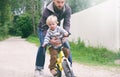 Father teaches his little child to ride bike in spring summer park, catches boy when he falls. Happy family moments. Time together Royalty Free Stock Photo