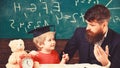 Father teaches son mathematics. Arithmetic lesson concept. Teacher in formal wear and pupil in mortarboard in classroom Royalty Free Stock Photo