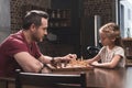 Father teaching daughter to play chess