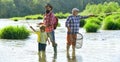 Father teaching his son fishing against view of river and landscape. Happy weekend concept. 3 men fishing on river in Royalty Free Stock Photo