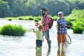 Father teaching his son fishing against view of river and landscape. Man with his son and father on river fishing with