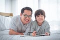 Father teaching his son school homework, lying on the bed with smile for Happy parenting concept