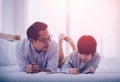 Father teaching his son school homework, lying on the bed with smile for Happy parenting concept