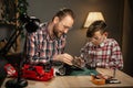 Father teaching his son for soldering remote controlled car in the evening at home. Man and boy fixing broken toy. Royalty Free Stock Photo