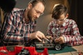 Father teaching his son for soldering and repair remote controlled car at home. Man and boy fixing broken toy. Royalty Free Stock Photo