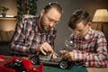 Father teaching his son for soldering and repair remote controlled car at home. Man and boy fixing broken toy. Royalty Free Stock Photo