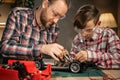 Father teaching his son for soldering and repair remote controlled car at home. Man and boy fixing broken toy. Royalty Free Stock Photo