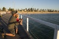 Father teaching little young son to be a fisherman, fishing together on sea dock embankment enjoying and learning using the fish r Royalty Free Stock Photo