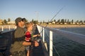 Father teaching little young son to be a fisherman, fishing together on sea dock embankment enjoying and learning using the fish r Royalty Free Stock Photo