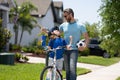 Father teaching son riding bike. Dad helping child son to ride a bicycle in american neighborhood. Child in bike helmet