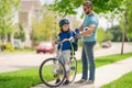 Father teaching son riding bike. Dad helping child son to ride a bicycle in american neighborhood. Child in bike helmet