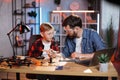 Father teaching son to repair broken details from laptop