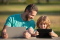 Father teaching son to use laptop, dad and school boy child looking computer screen and tablet, playing game, watching Royalty Free Stock Photo