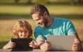 Father teaching son to use laptop, dad and school boy child looking computer screen and tablet, playing game, watching Royalty Free Stock Photo