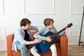 Father teaching teenager son to playing acoustic guitar at home, happy single parent family relations, fathers support and care Royalty Free Stock Photo