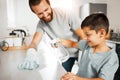 Father teaching young son cleaning chores in the family home having fun and bonding together. Smiling and loving father Royalty Free Stock Photo