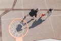 Father and teenage daughter playing basketball outside at court, high angle view above hoop net.