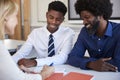 Father And Teenage Son Having Discussion With Female Teacher At High School Parents Evening