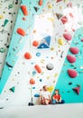 Father and teenage son sitting near the indoor climbing wall. They resting after the active climbing. Happy parenting concept Royalty Free Stock Photo