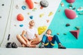 Father and teenage son sitting near the indoor climbing wall. They resting after the active climbing. Happy parenting concept Royalty Free Stock Photo