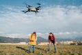 Father and Teenager boy son dressed yellow jacket piloting a modern digital drone using remote controller. Modern technology