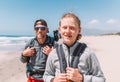 Father with teenager son with backpacks walking by the sandy seaside beach. They smiling and looking at the camera. Active happy