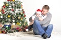 Father and their small child sits near Christmas tree Royalty Free Stock Photo