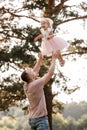 Father throws baby in nature, girl flies in the sky. Portrait dad with child together. Daddy, little daughter outdoors