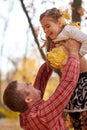 Father throws the daughter high up in autumn city park. They posing, smiling, playing. Bright yellow trees. Royalty Free Stock Photo